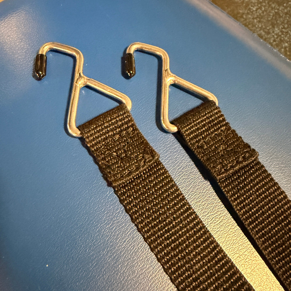 Two brown straps with gold hooks on a blue surface