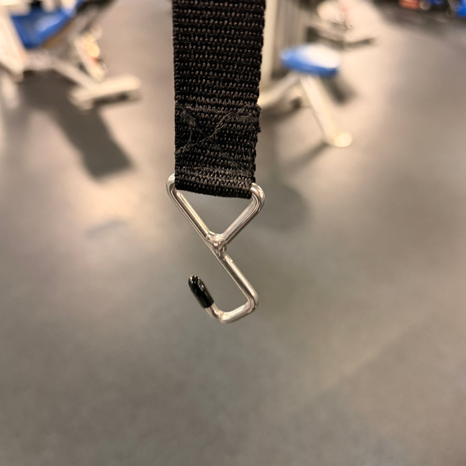 Black strap with a metal hook on a gray surface