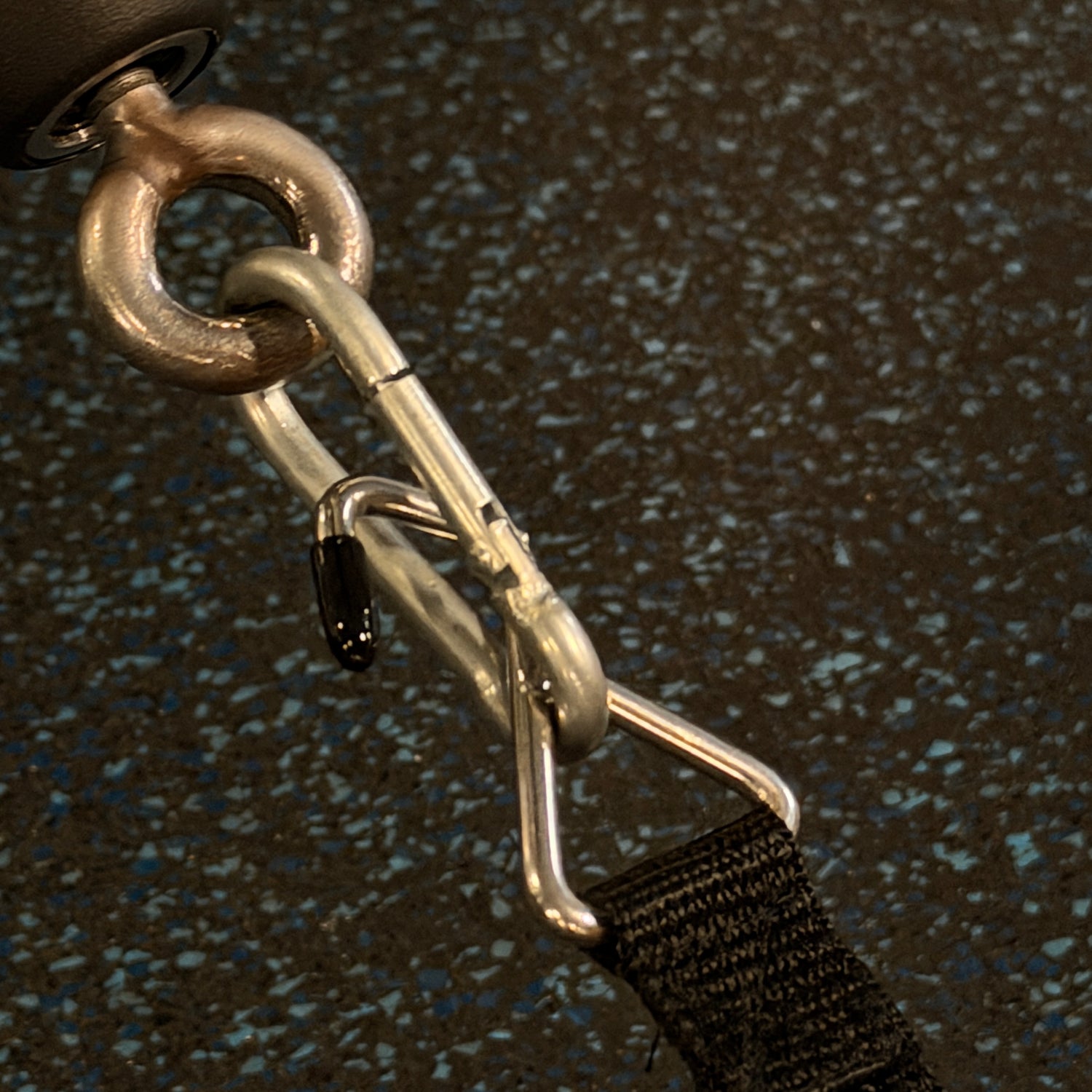 Metal shackle with a black strap on a textured dark background