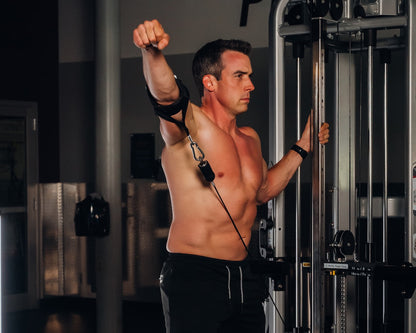 Man using cable arm cuff for shoulder workout in gym